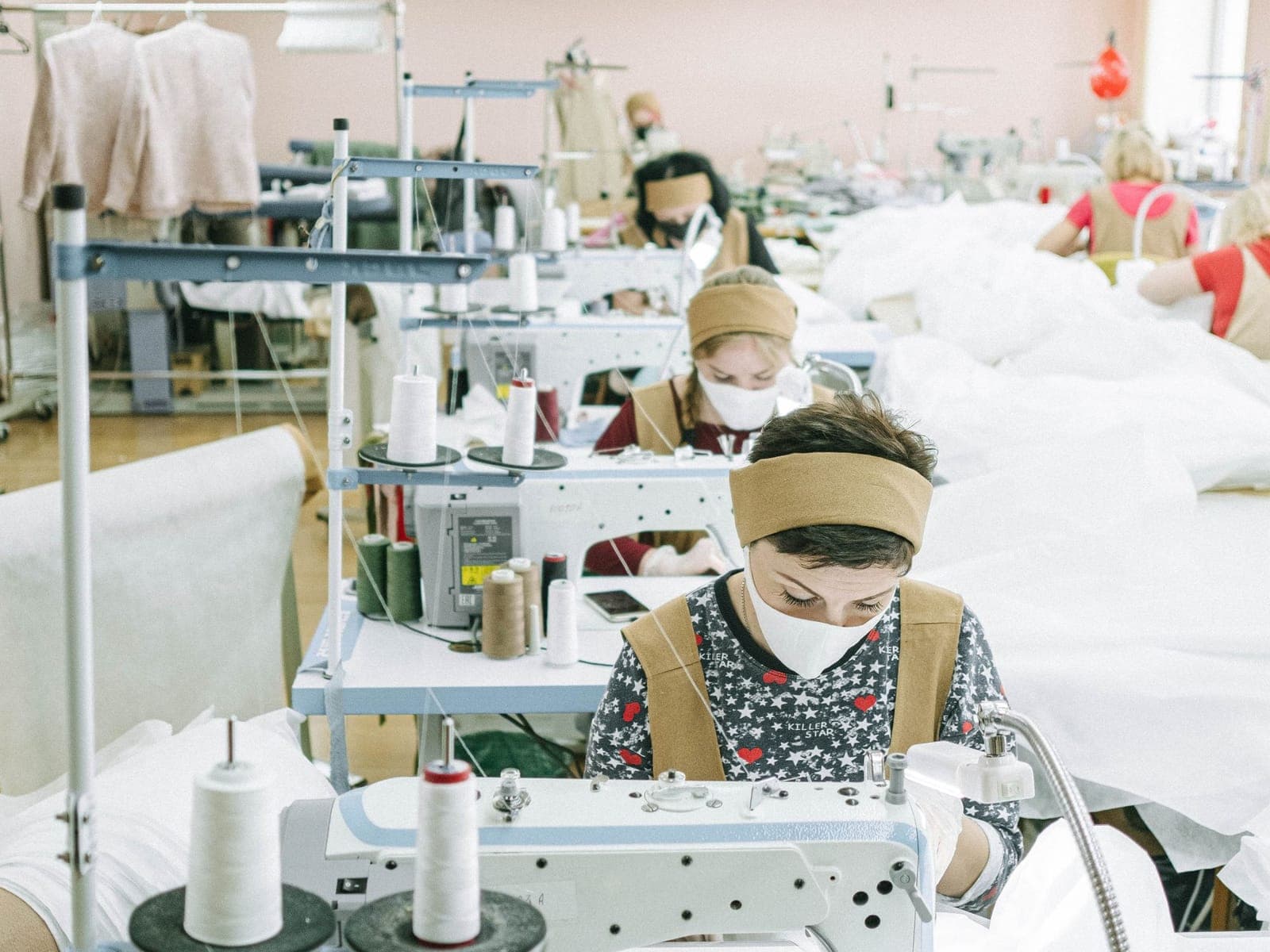 Row of industrial sewing machines running during bulk garment production