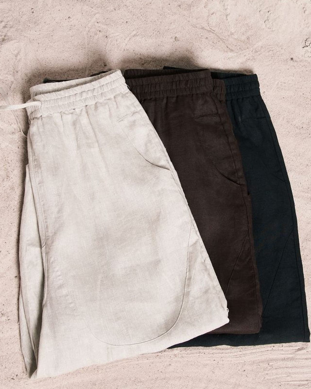 Three pairs of folded knit shorts in neutral shades laid flat